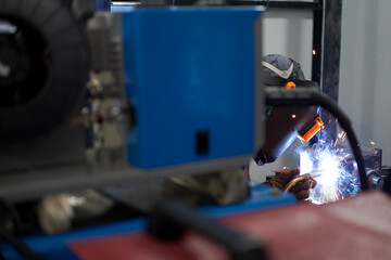 Welder performing Tungsten Inert Gas welding process (TIG) on stainless steel. TIG welding uses the heat generated by an electric arc struck between a non-consumable tungsten electrode and the work