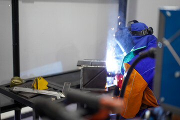 Welder performing Tungsten Inert Gas welding process (TIG) on stainless steel. TIG welding uses the heat generated by an electric arc struck between a non-consumable tungsten electrode and the work