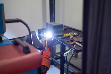 Welder performing Tungsten Inert Gas welding process (TIG) on stainless steel. TIG welding uses the heat generated by an electric arc struck between a non-consumable tungsten electrode and the work