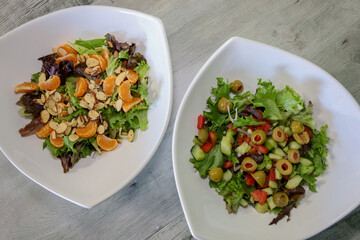 Top view of two different types of salads in white bowls.