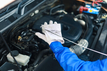 Close-up of a car mechanic checking the engine oil. Inspect and maintain the car engine to ensure it is in perfect working order.