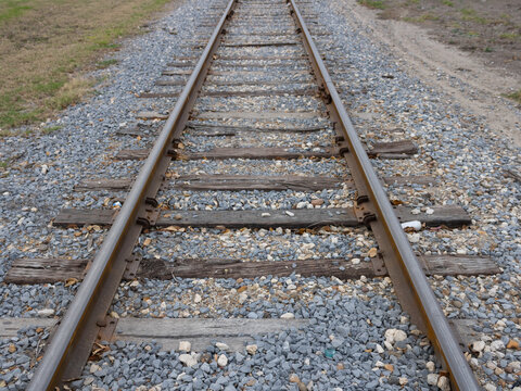 A photograph of railroad tracks stretching into the distance, capturing the symmetry, texture, and timeless feel of rail travel through a quiet landscape.