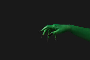 Green hand of witch on black background. Halloween celebration