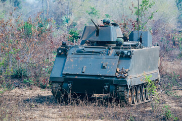 Fototapeta premium Armored on Patrol, A armored vehicles carrying armed soldiers advances along a dirt path during a field training exercise.