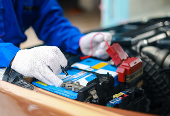 Auto mechanics check car engines with digital multimeters, test batteries and fuse boxes, and inspect electrical systems. Car service and maintenance.