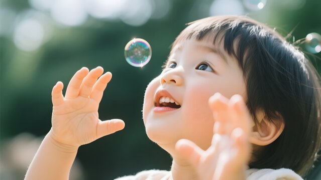 Child joyfully reaching for floating bubbles in a sunny outdoor setting - Powered by Adobe