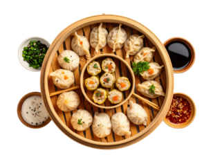 A top-down view of a variety of steamed dim sum dumplings, including buns and shumai, in a traditional bamboo steamer with various dipping sauces.
