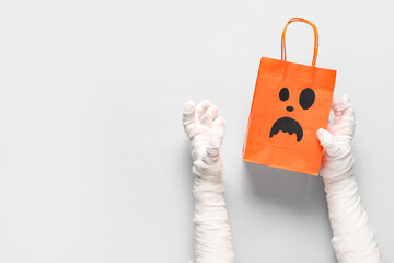 Mummy hands with shopping bag on grey background. Halloween celebration