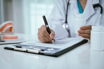 A dentist explains oral health using a dental model, demonstrating proper teeth alignment and hygiene during a patient consultation at a modern dental clinic or hospital.