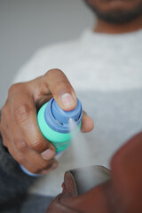 Hand applying spray in a shoe to remove odor 
