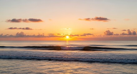 Ocean sunset with sun partially obscured by clouds waves in foreground