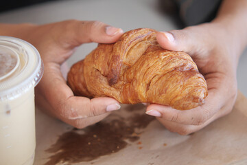 Holding a warm croissant beside an iced drink