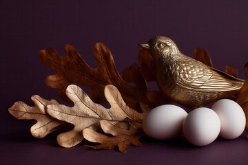 Obraz premium Small white eggs, brown oak leaves, and a gold bird figurine on a dark purple background, captured through macro photography using a macro lens for a close-up view.