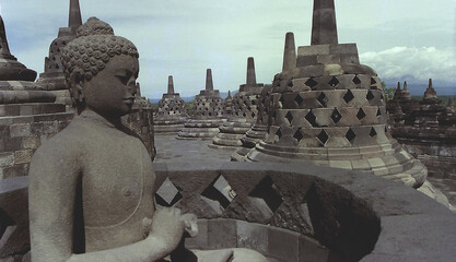 Fototapeta premium Borobudur Temple Compounds (Buddhist pagodas and Buddha statues ) / ボロブドゥール寺院遺跡群，境内の内側 仏塔と仏像の石碑群 - 横アングル撮り