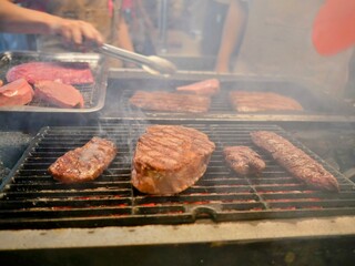Grilling fresh steaks over open flame at a fine steak restaurant in Bangkok, Thailand, showcasing expert preparation and premium dining atmosphere.