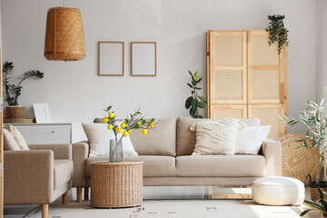 Comfortable beige sofas, wicker table and houseplants in interior of living room