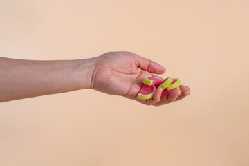 Fruit jelly mixed with sugar and hand on cream background