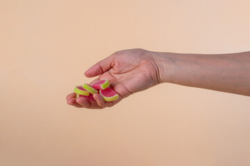 Fruit jelly mixed with sugar and hand on cream background
