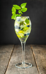 Refreshing classic mojito cocktail with lime and mint in wineglass on the rustic background. Selective focus.