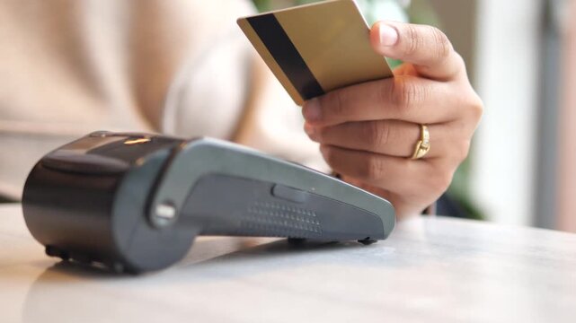 a hand making a contactless payment with a credit card at a pos terminal