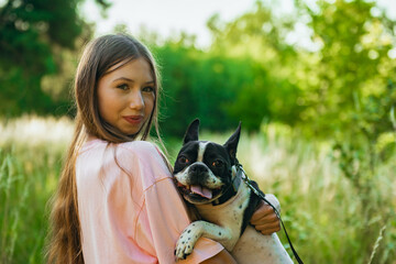 Beautiful teenage girl holds her beloved pet, a cute French bulldog dog.