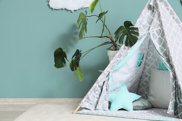 Interior of modern children's room with teepee and houseplant near mint wall, closeup © Pixel-Shot