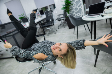 Caucasian woman having fun and lying on office chair. 