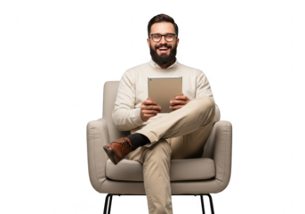 A smiling man with glasses and a beard is sitting comfortably in an armchair holding a tablet device and looking at the camera isolated on transparent