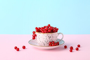 Cup with ripe red currant on color background, closeup