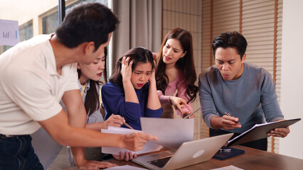 Asian business team confronting complex project challenges serious discussion office