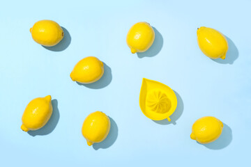 Fresh ripe lemons and juicer on blue background