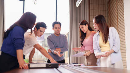 Asian business professionals collaborate discuss project strategy modern office workspace corporate environment analyzing documents team meeting brainstorming session