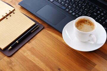 机にリング式のシステム手帳を広げ、淹れたてのコーヒー（カフェ・ラテ）を飲みながら、パソコンでデスクワークをしているイメージ
