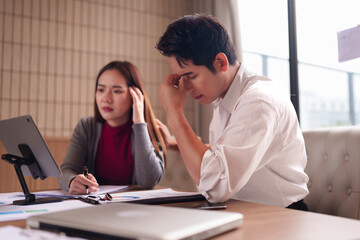 Asian Business Professionals Collaborating On Challenging Project Analyzing Data Reports Feeling Pressure In Modern Office