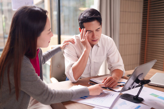 Asian business professionals face work stress colleague provides support during challenging financial report review office meeting