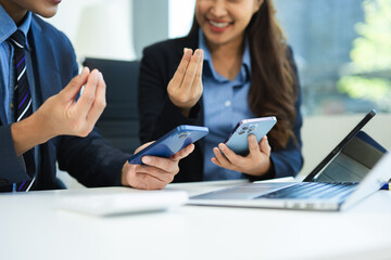 Business documents on office table with smart phone and laptop and two colleagues discussing data in the background