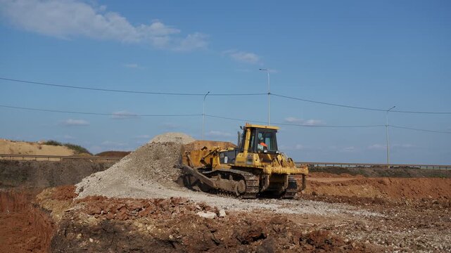 Yellow bulldozer moving soil at a construction site. Clip