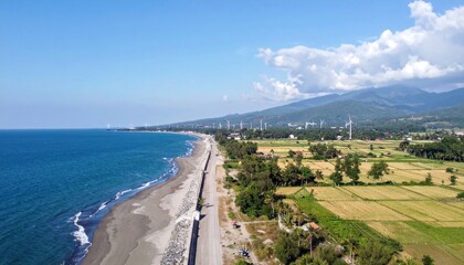 Obraz premium Scenic coastal panorama with wind turbines and rural farmland extending inland