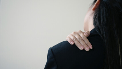 Businesswoman is massaging her shoulder with her hands. Shoulder pain from work fatigue and muscle...