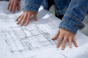 Hands of architect reviewing building blueprints on table