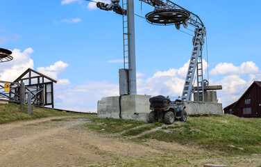 An abandoned ATV near a ski lift symbolizes the combination of active recreation and modern technology against a natural landscape.