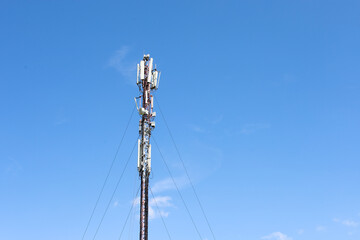 A modern cell tower standing against a clear blue sky is a symbol of technological progress and global connectivity.