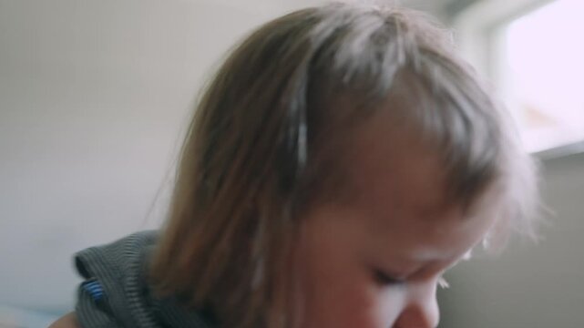 Young European child rush to put on summer shirt in bedroom, close-up frontal