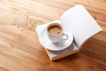 ページを開いたペーパーバック（洋書）とコーヒーの入ったコーヒーカップで、コーヒーを飲みながら読書を楽しんでいるイメージ

