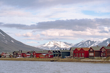 Row of colorful houses on the shore of the Adventfjorden fjord in Longyearbyen with rugged mountains in the background