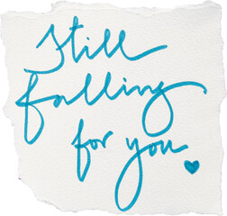 Blue handwritten quote 'still falling for you' on textured paper isolated on white background