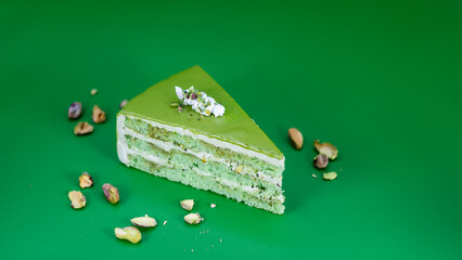 Pistachio Kunafa Viral Green mousse cake slice topped with pistachios on vibrant green background suitable for dessert menus or culinary presentations