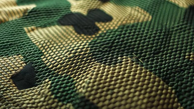 Close-up of a textured fabric showcasing a unique green and brown camouflage pattern, perfect for outdoor settings, military themes, and design projects.