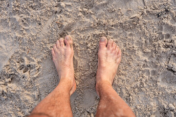 Bare Feet Standing On Dry Sand Surface With Footprints
