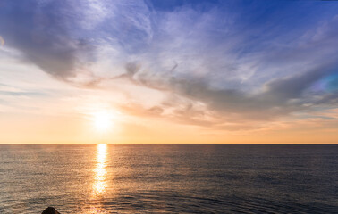 scenic sunrise or sunset above sea water with beautiful ocean vawes , nice golden evening clouds above horizon and awesome blue sky